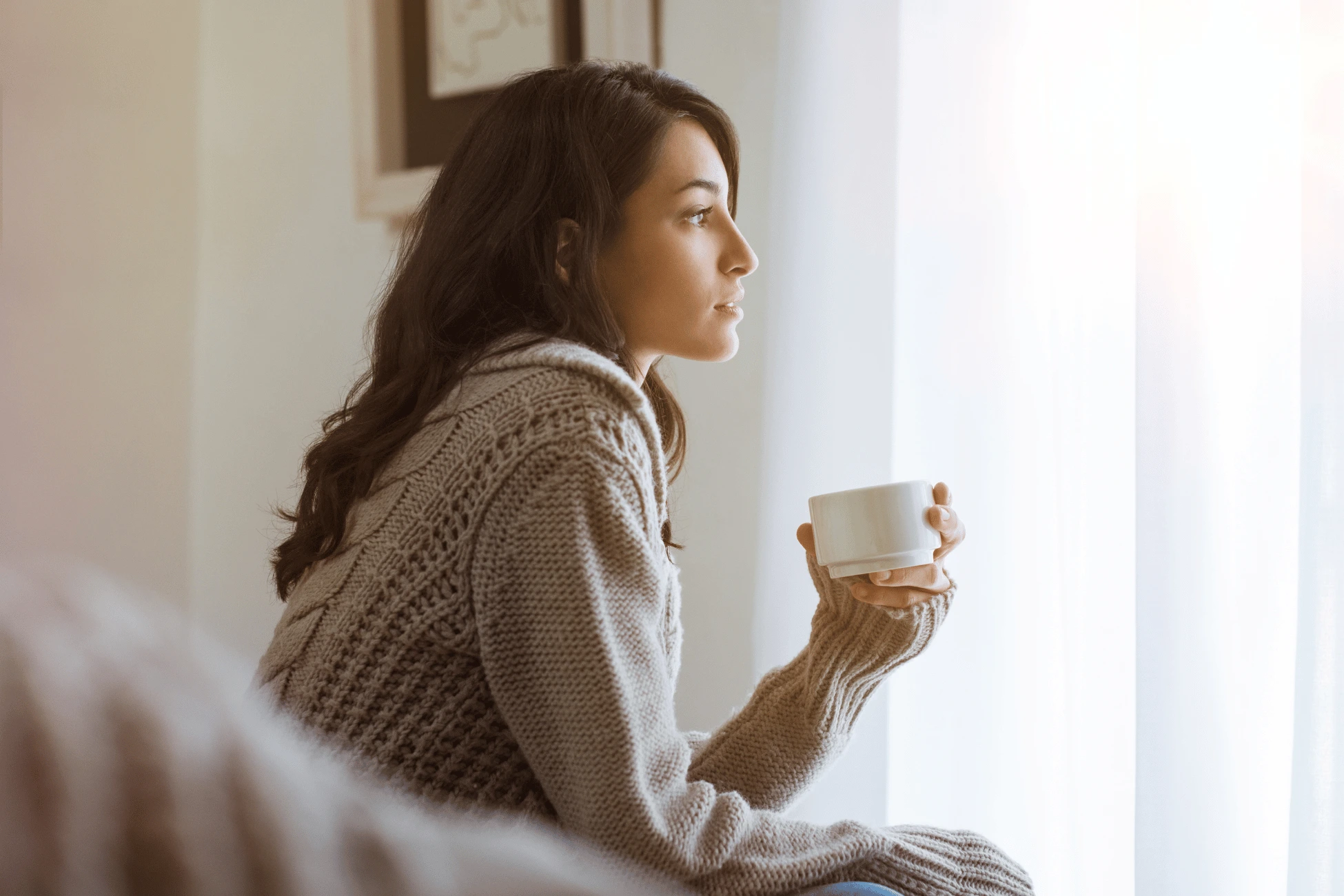 Femme assise près de la fenêtre dans un moment de réflexion