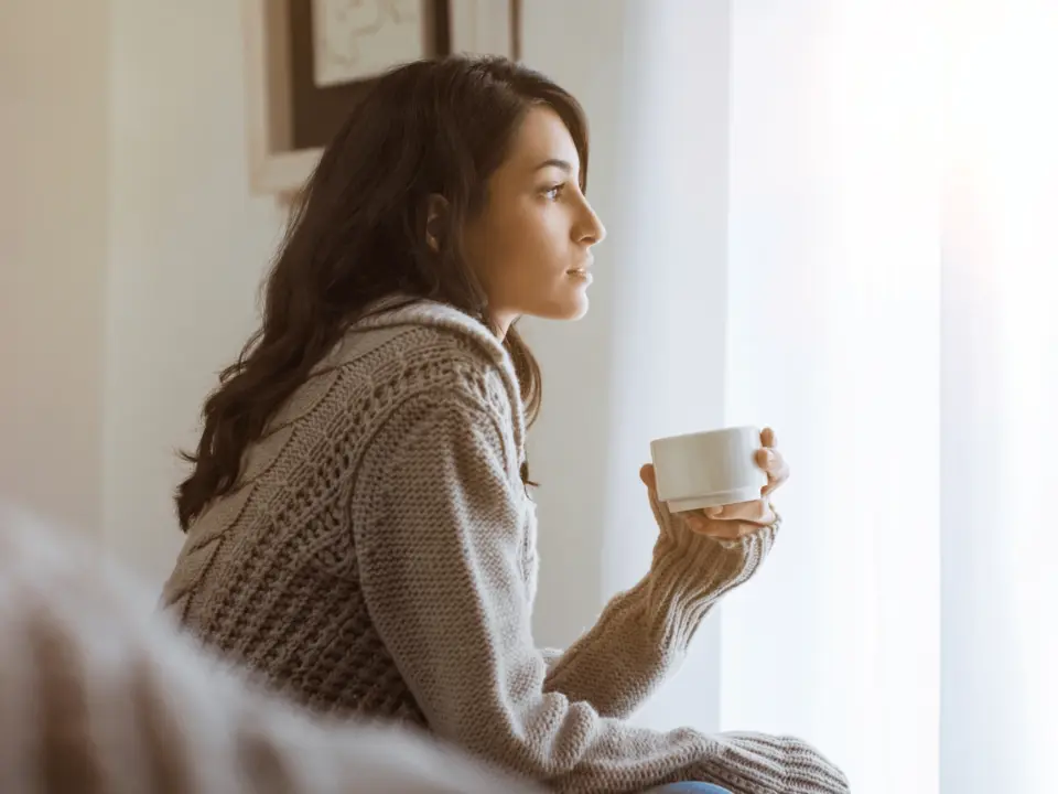 Mujer sentada junto a la ventana en un momento de reflexión