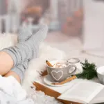 Donna sul divano con calze calde in un’atmosfera invernale hygge