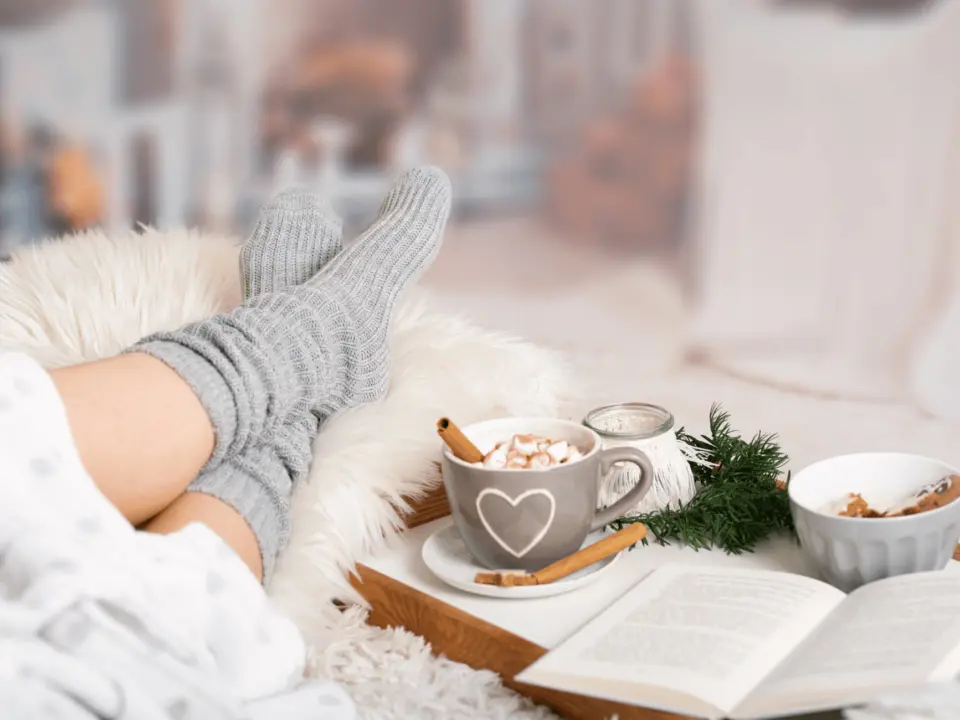 Mulher no sofá com meias aconchegantes em ambiente de inverno acolhedor