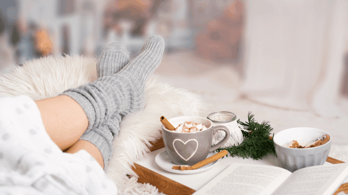 Hygge_im-Alltag,-Winter-Routine_für_Frauen,_Frau_auf_Sofa_mit_Kuschensocken_für_mehr_Wohlbefinden_im_Winter