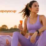 Imagen fotorealista donde se ve a una mujer deportista con ropa de deporte aguantando su copa menstrual papaya cup