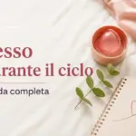 Coppetta mestruale, quaderno con cuore e ramo su lenzuola bianche, con titolo su sesso e ciclo mestruale.