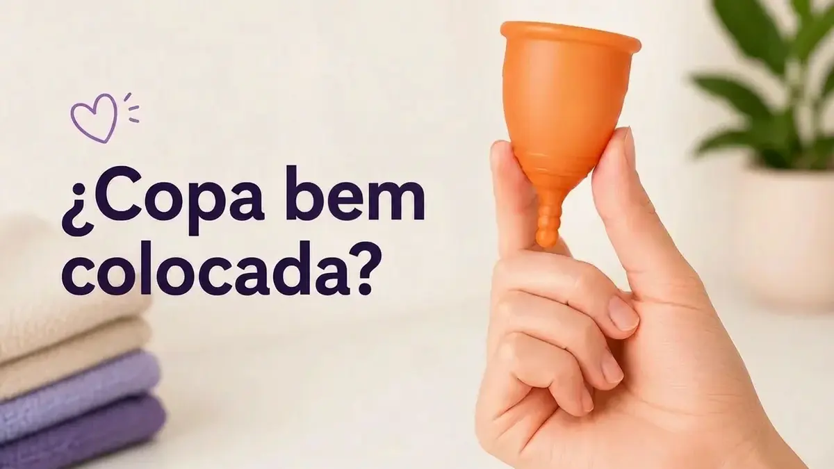 Mão segura copa menstrual laranja com a pergunta "¿Copa bien colocada?" e um coração roxo.