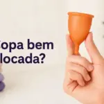 Mão segura copa menstrual laranja com a pergunta "¿Copa bien colocada?" e um coração roxo.