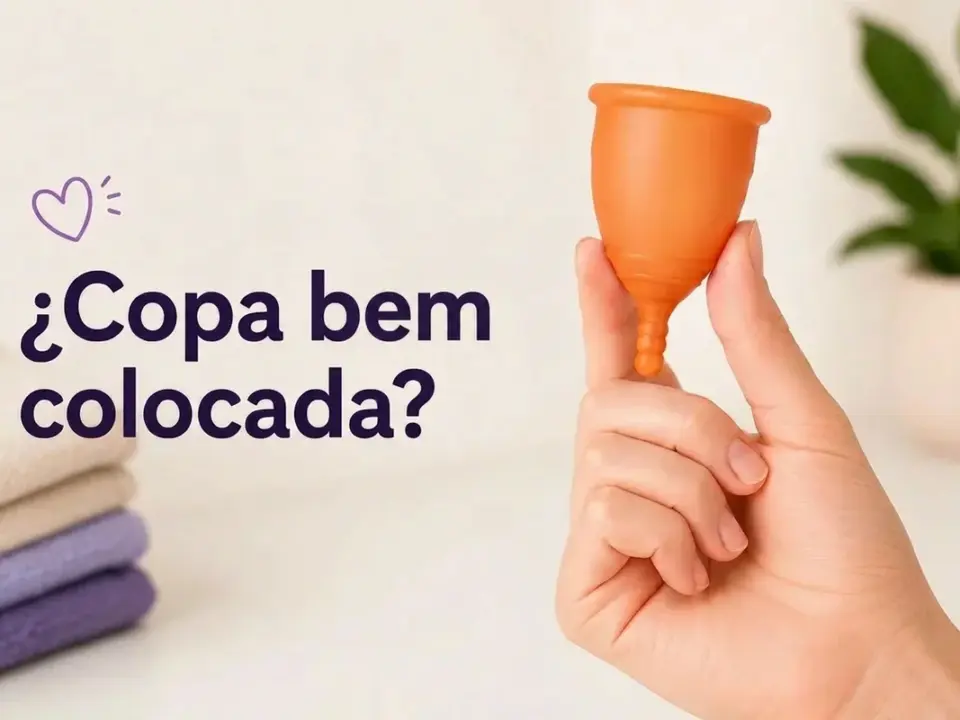 Mão segura copa menstrual laranja com a pergunta "¿Copa bien colocada?" e um coração roxo.